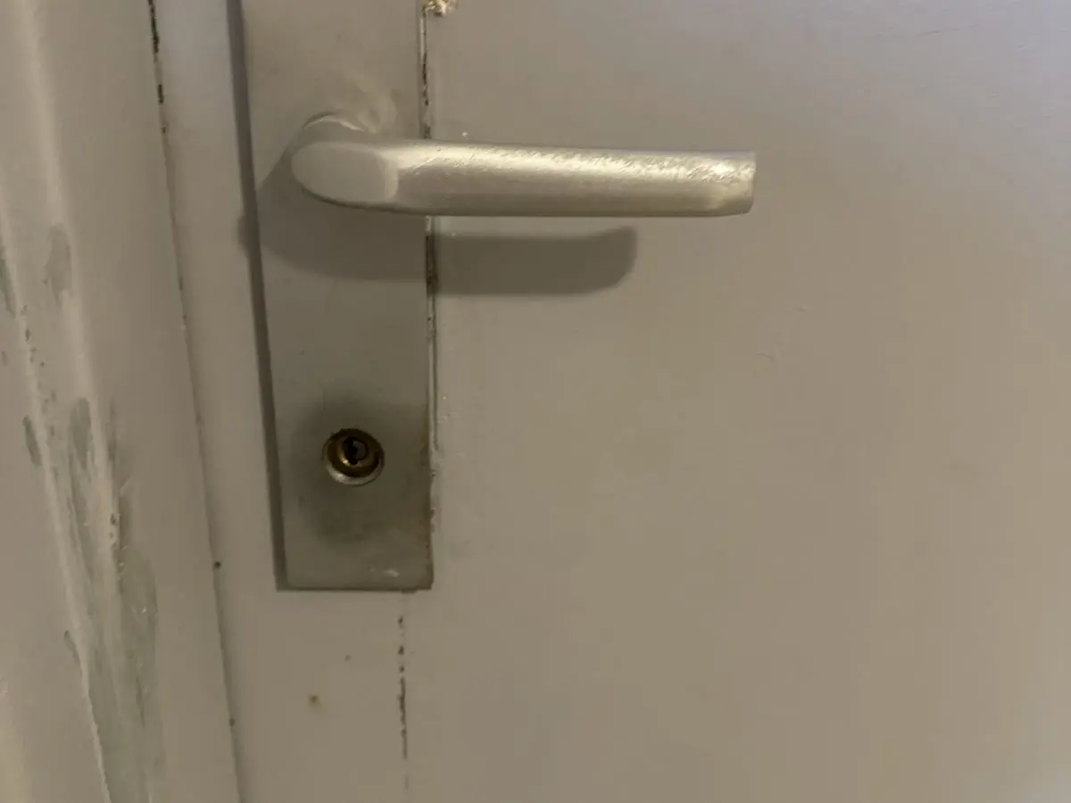 Poignée et cylindre sur une porte palière marquée par l’usage