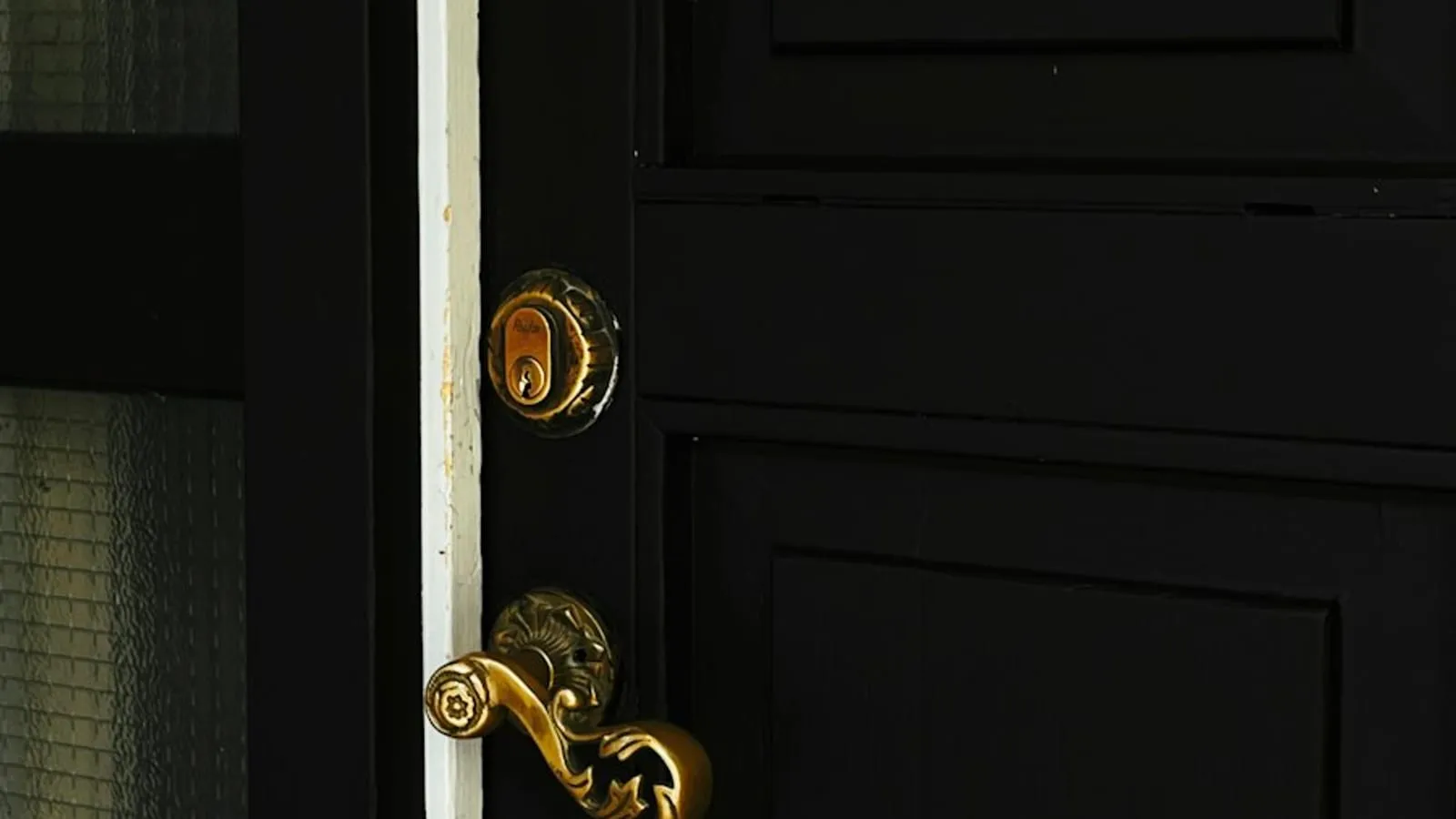 Poignée et serrure dorées sur une porte d'entrée noire, fermée