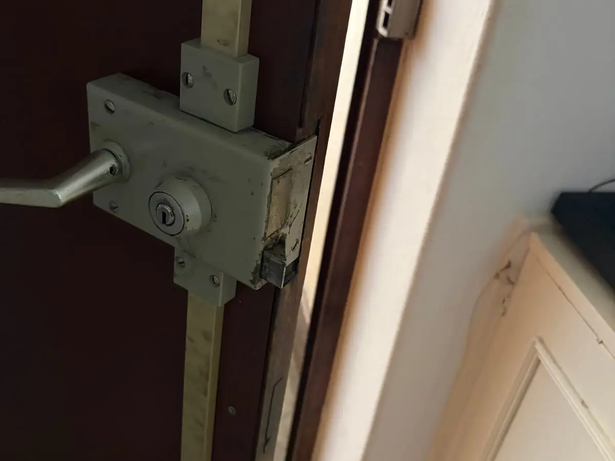 Serrure multipoints en applique sur une porte ancienne, tringles verticales apparentes